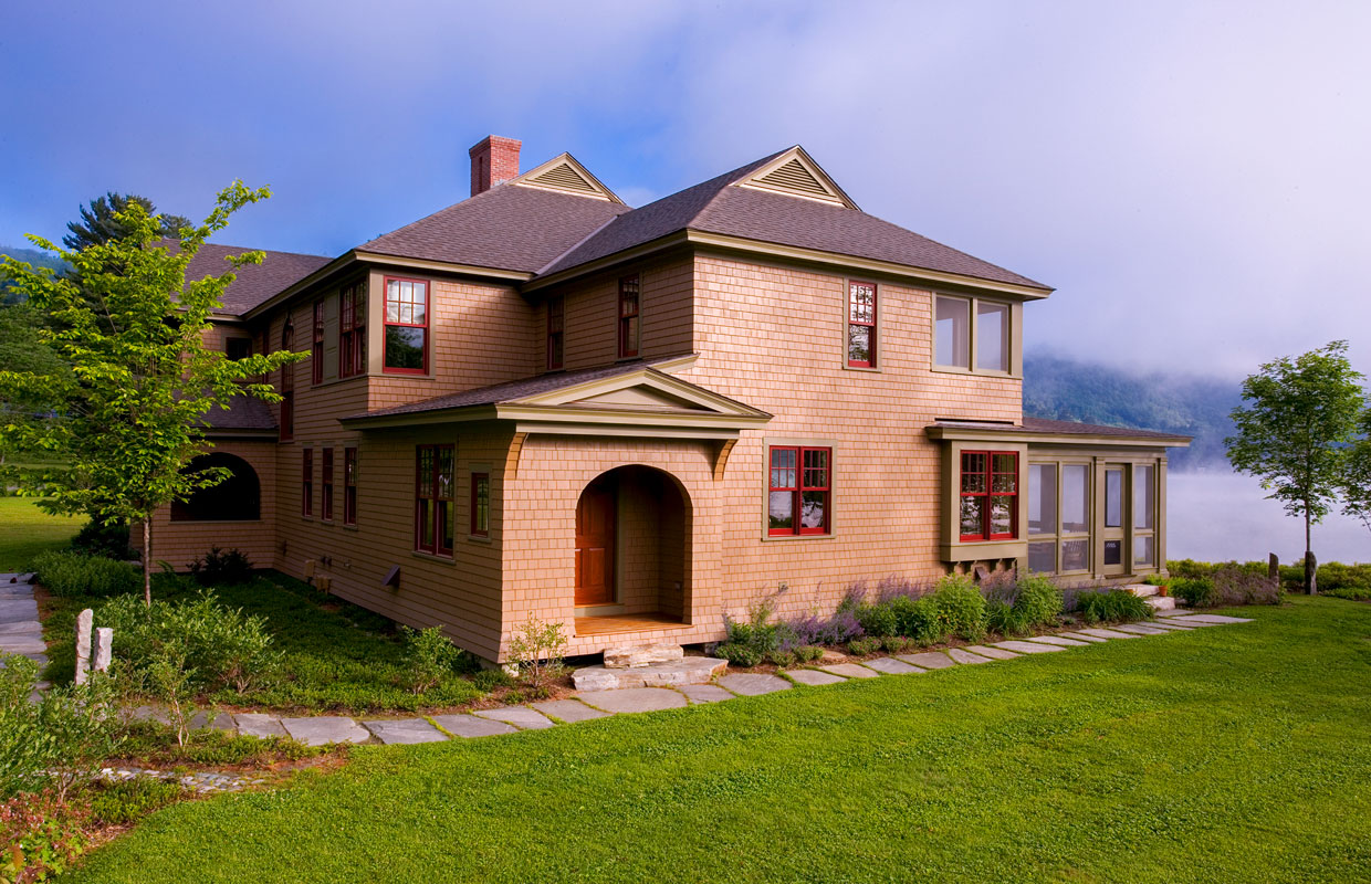 house on a lake with green lawn and fog on the water