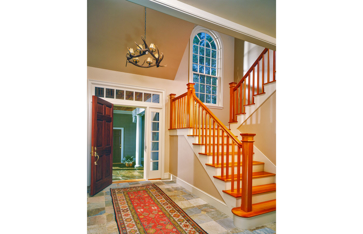 large wooden staircase with a large window on the first landing