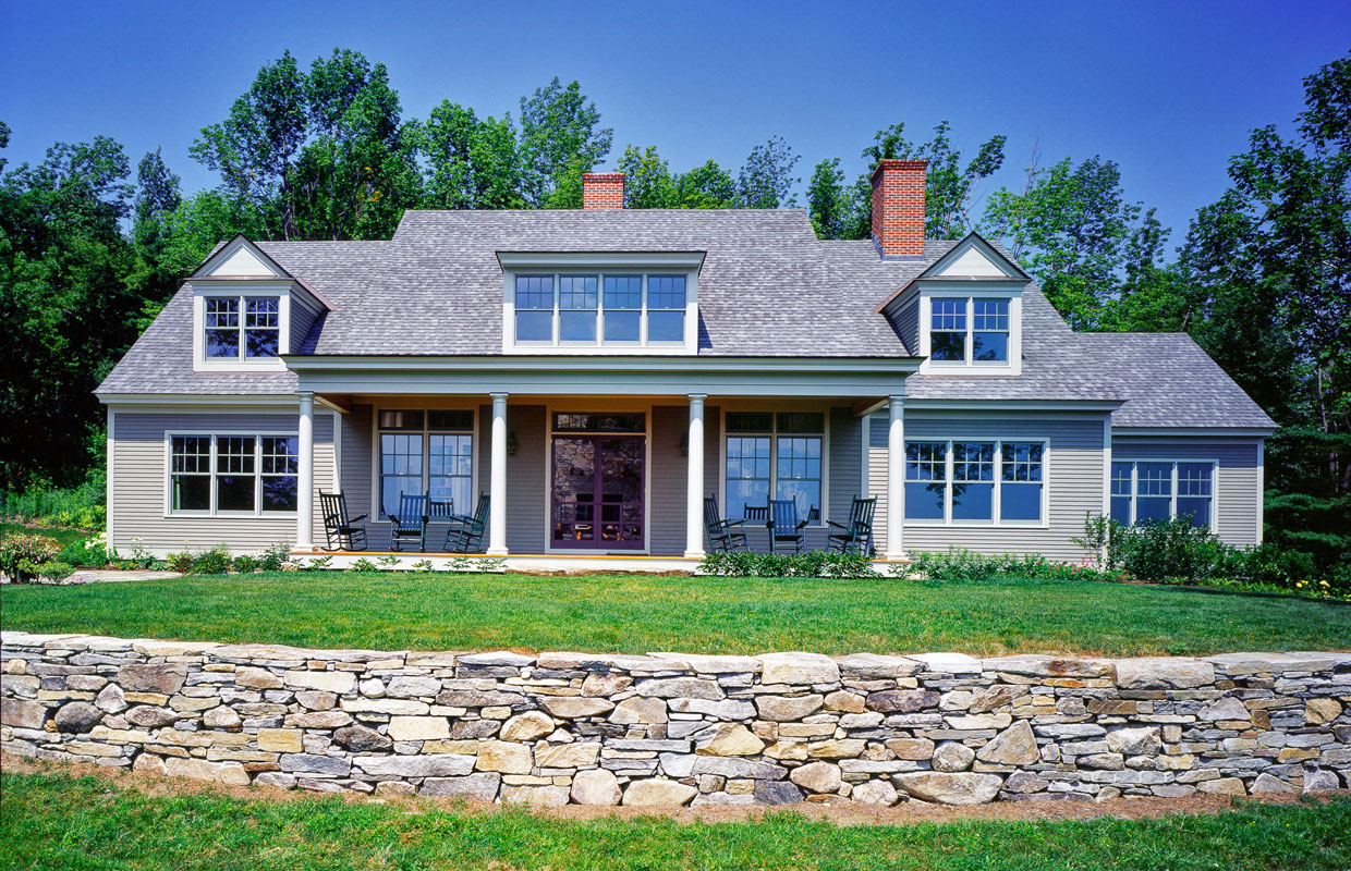 big gray house with a stone wall out front