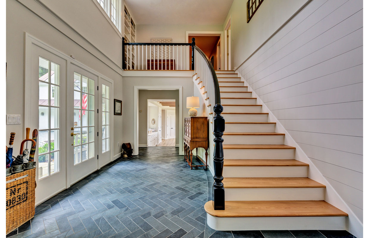 large staircase going up with a gray tile floor and open entryway below