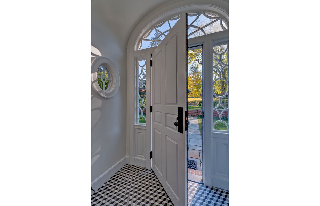 view from inside of a large white front door with black and white checker tile flooring
