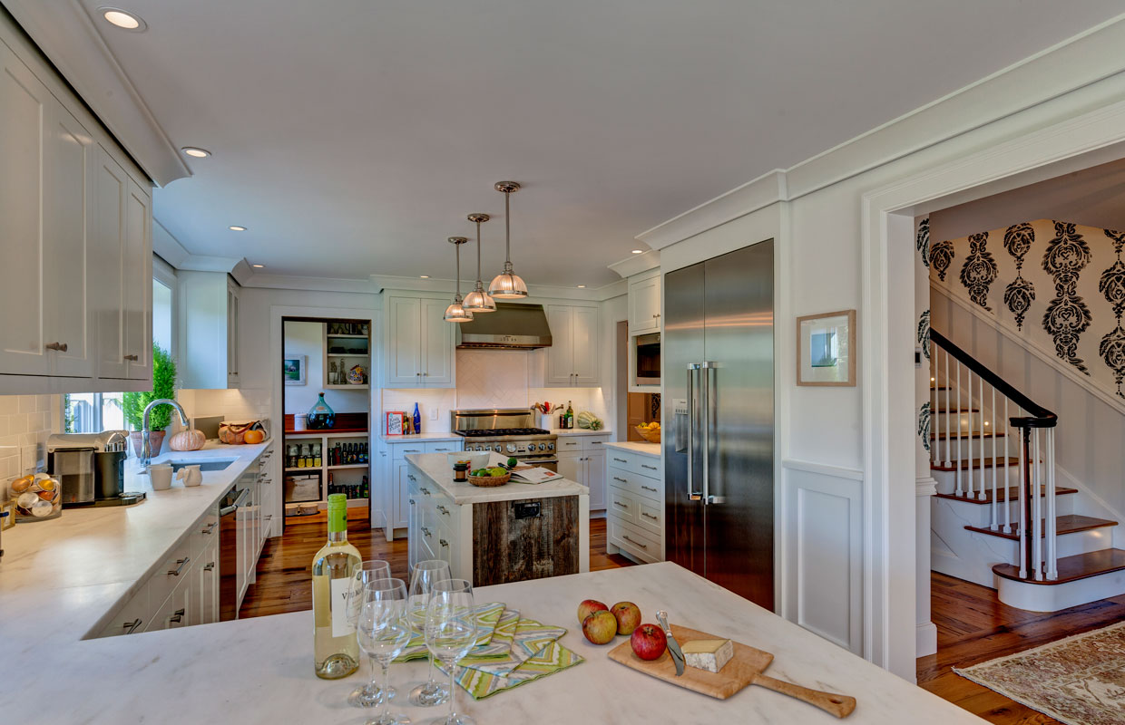 large white kitchen with a view of a staircase to the right