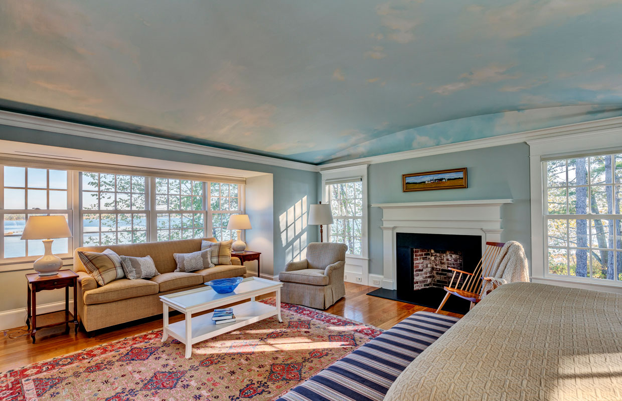 large living room with a fireplace and a blue sky scene painted on the ceiling