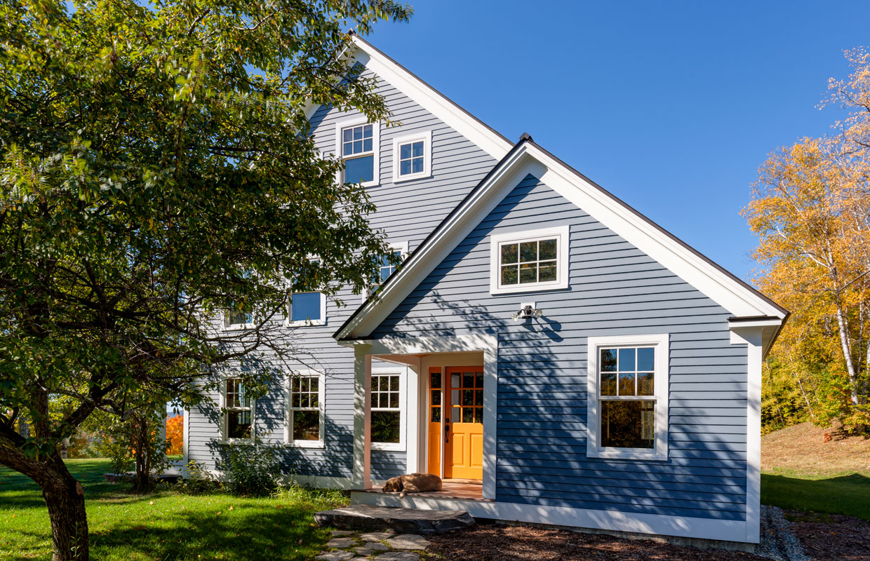 blue house with a wooden door and tree out front view from the gable end