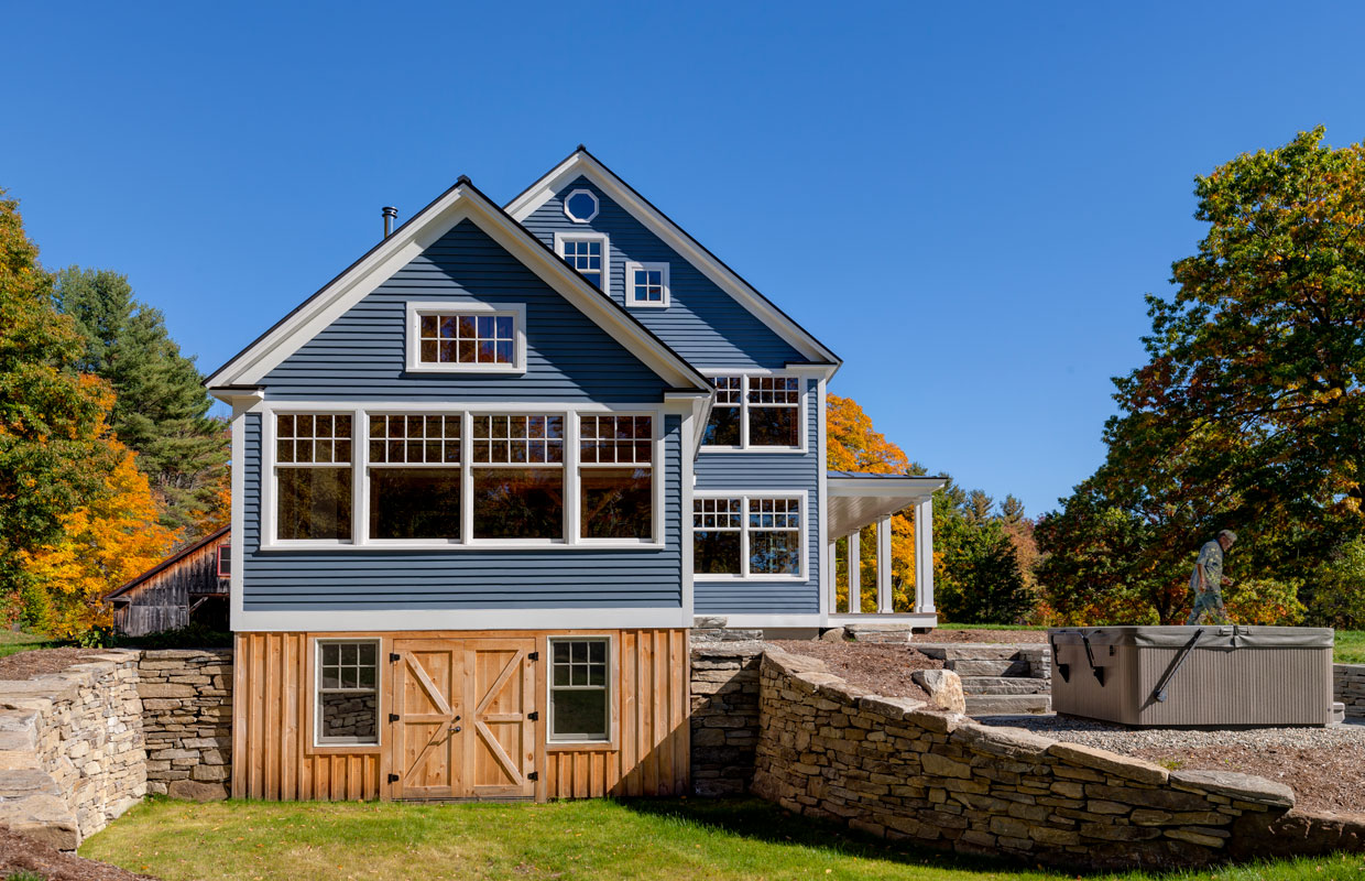 blue house with lots of windows and a wood-framed walk out basement and stonework