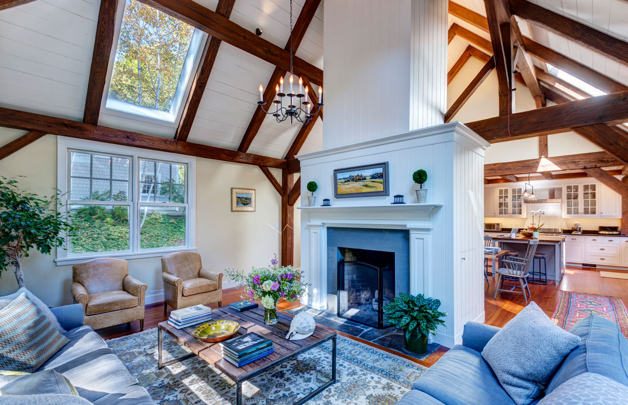 great room with white fireplace and exposed beams