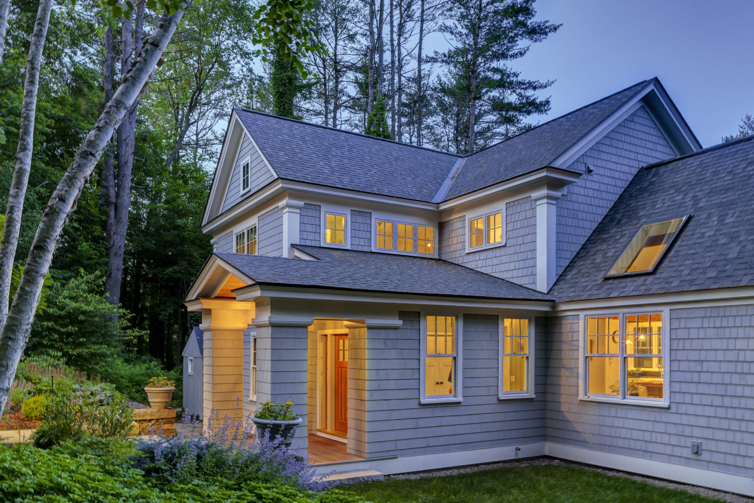 gray house at dusk with lights on inside