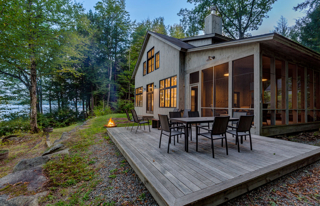 lakeside cottage at dusk with an outdoor fire pit and a deck