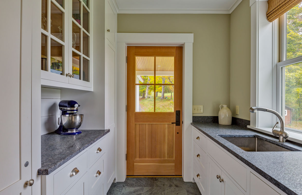 wooden door with 4 window panes from the inside of a kitchen