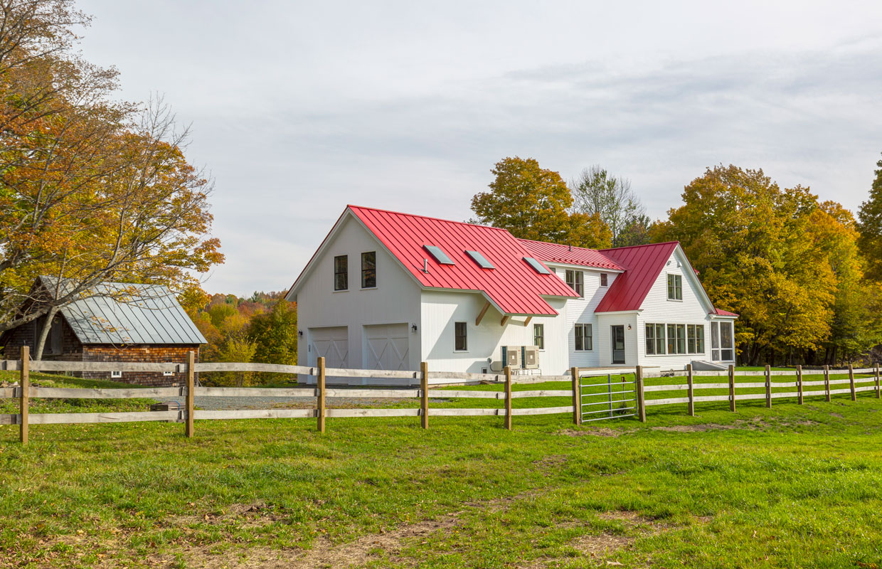 white house with a red roof with a large yard and wooden fence