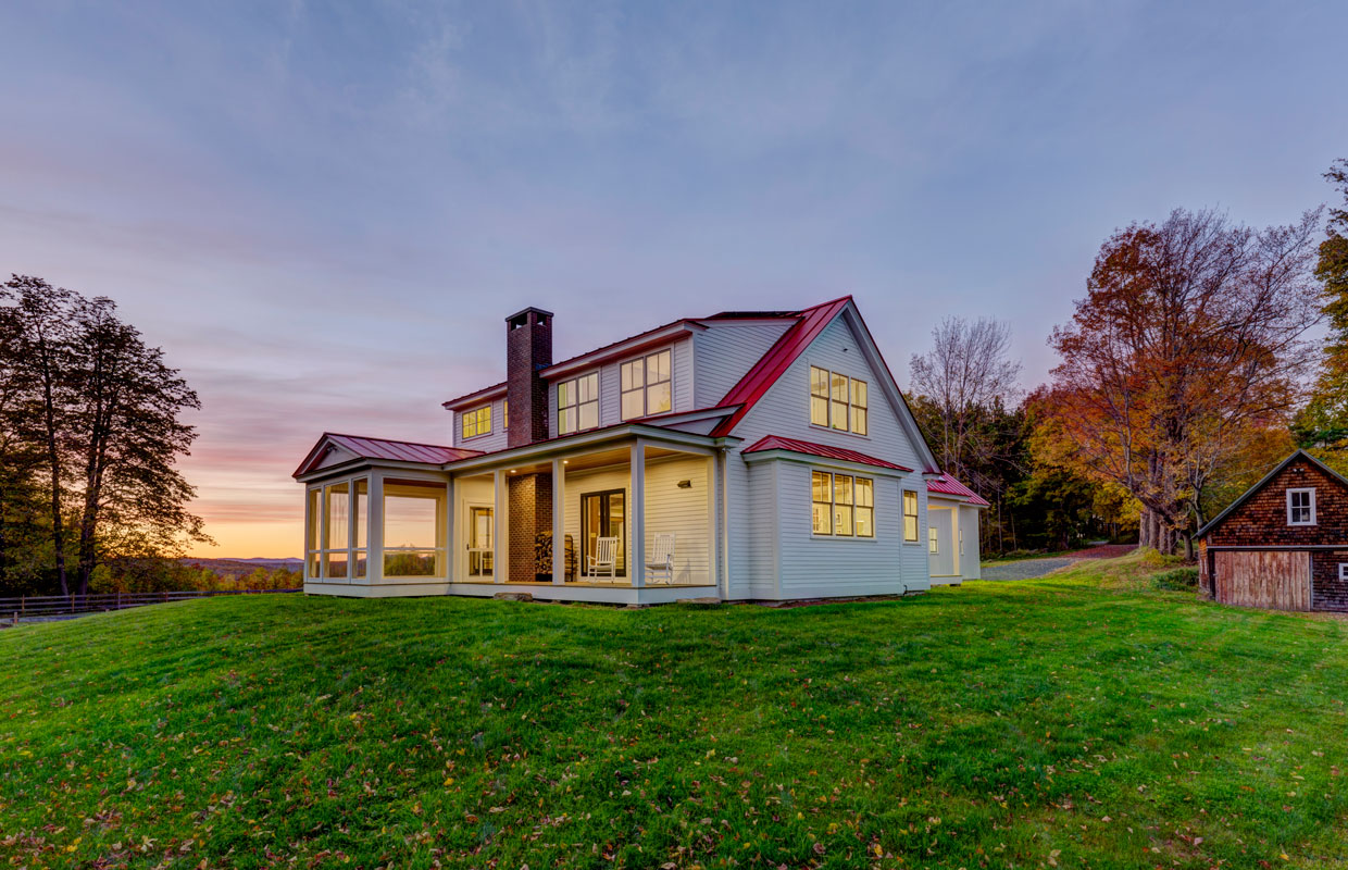 large white house with a red roof and chimney at dusk
