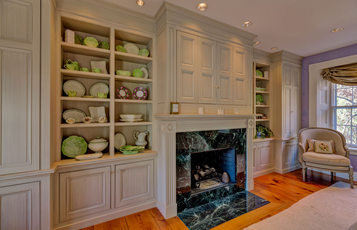 fireplace in a white built-in cabinet wall with green and white china