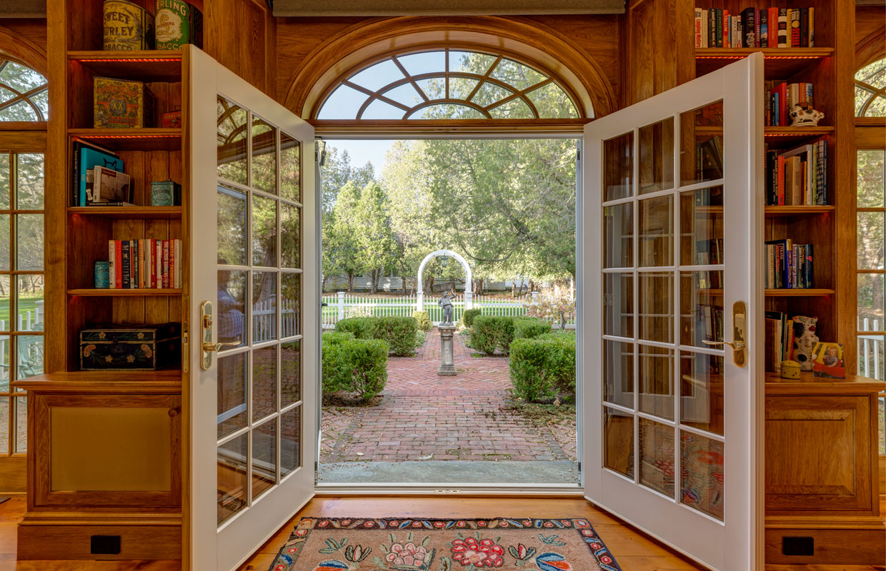 view of a garden from inside large open french doors with window panes