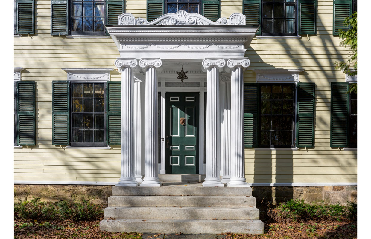 front door of a yellow house with columns and a green door