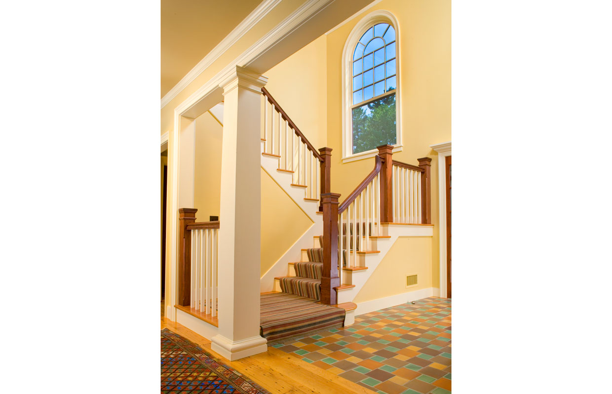 large yellow staircase with a colorful tile floor