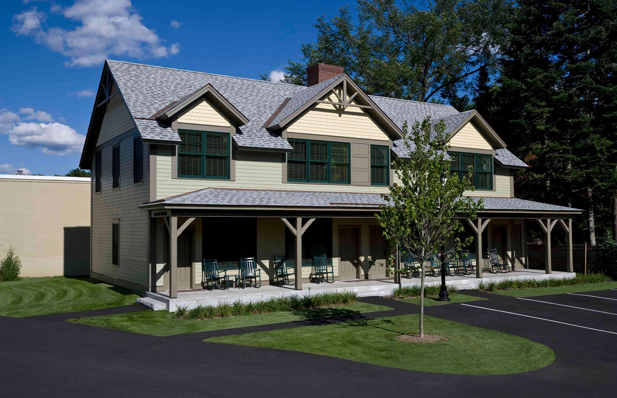 tan building with a farmer's porch and a tar parking area