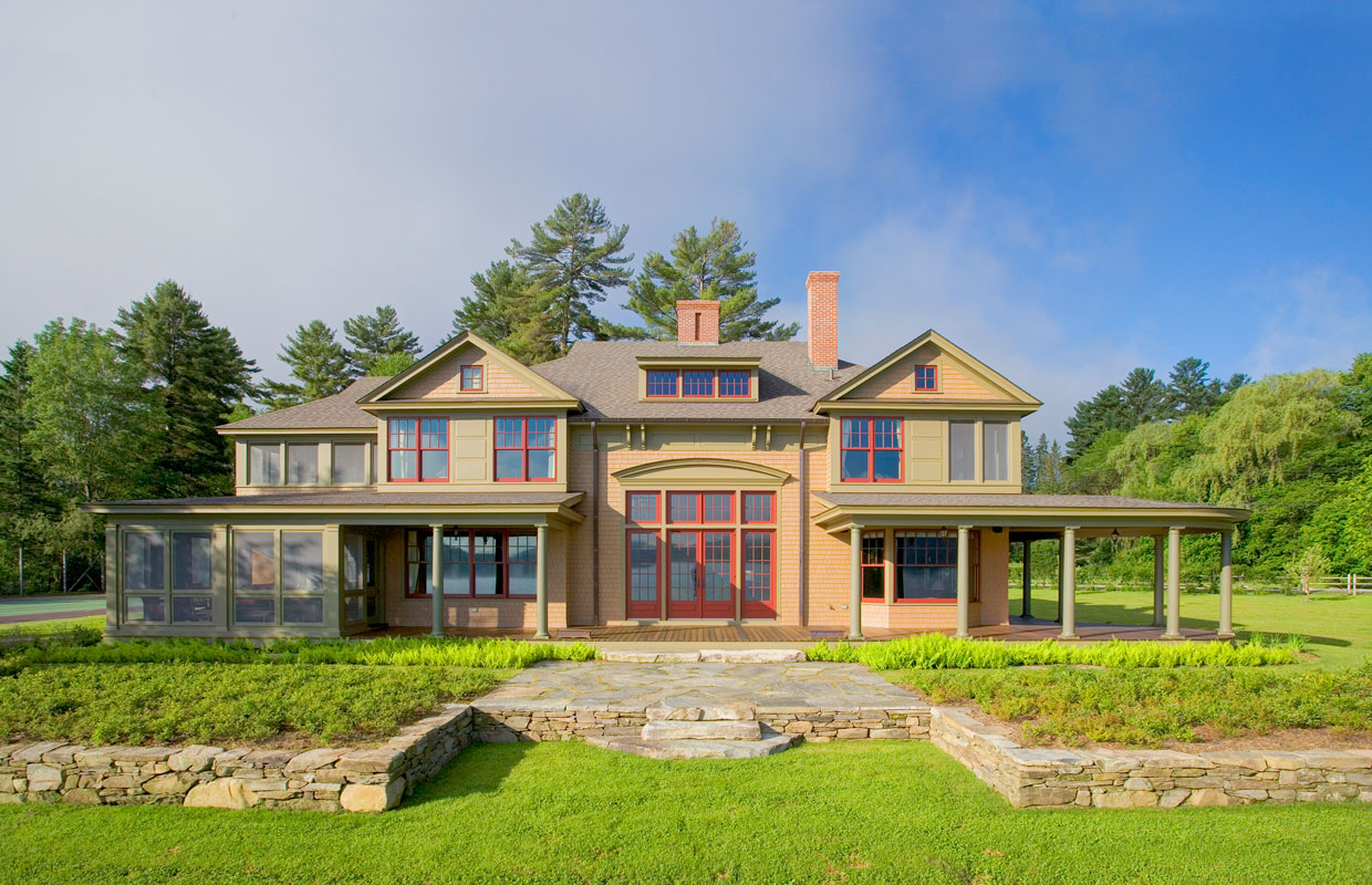 large tan house with red trim and stone work out front