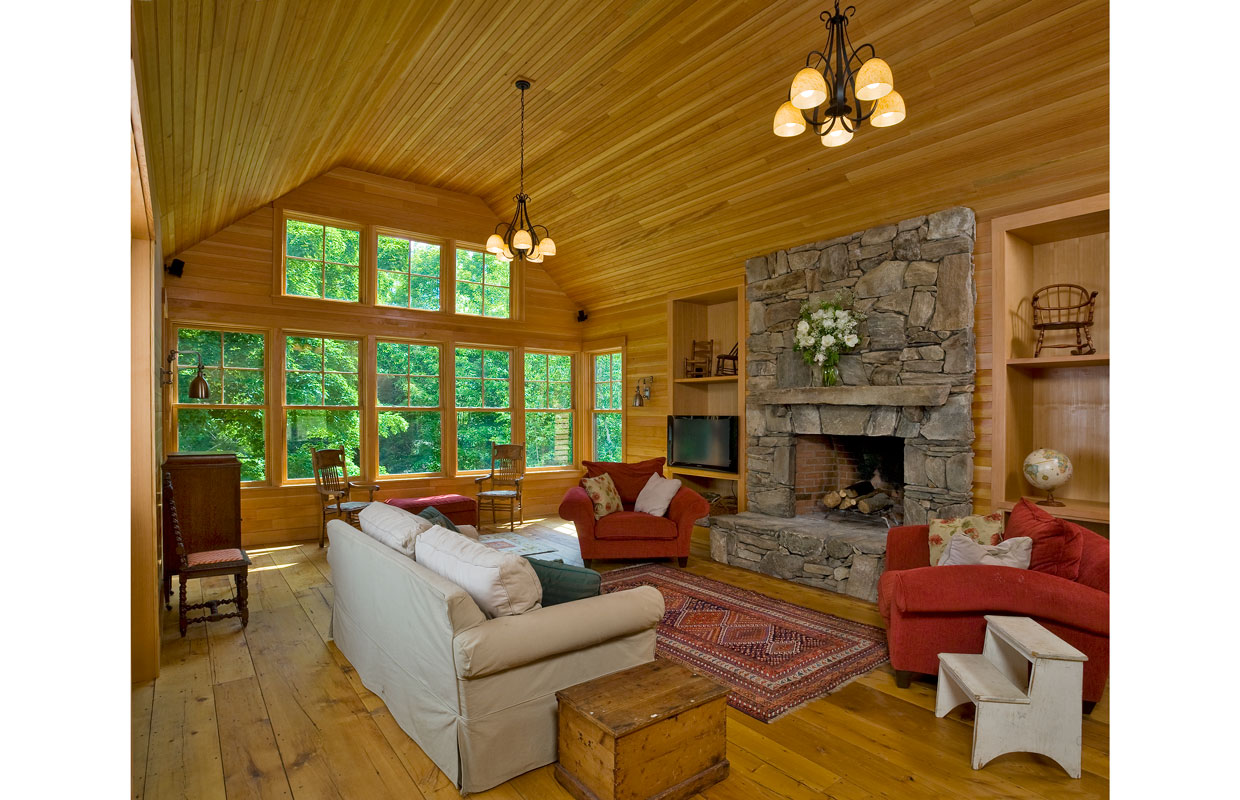 great room with a field stone fireplace and large windows
