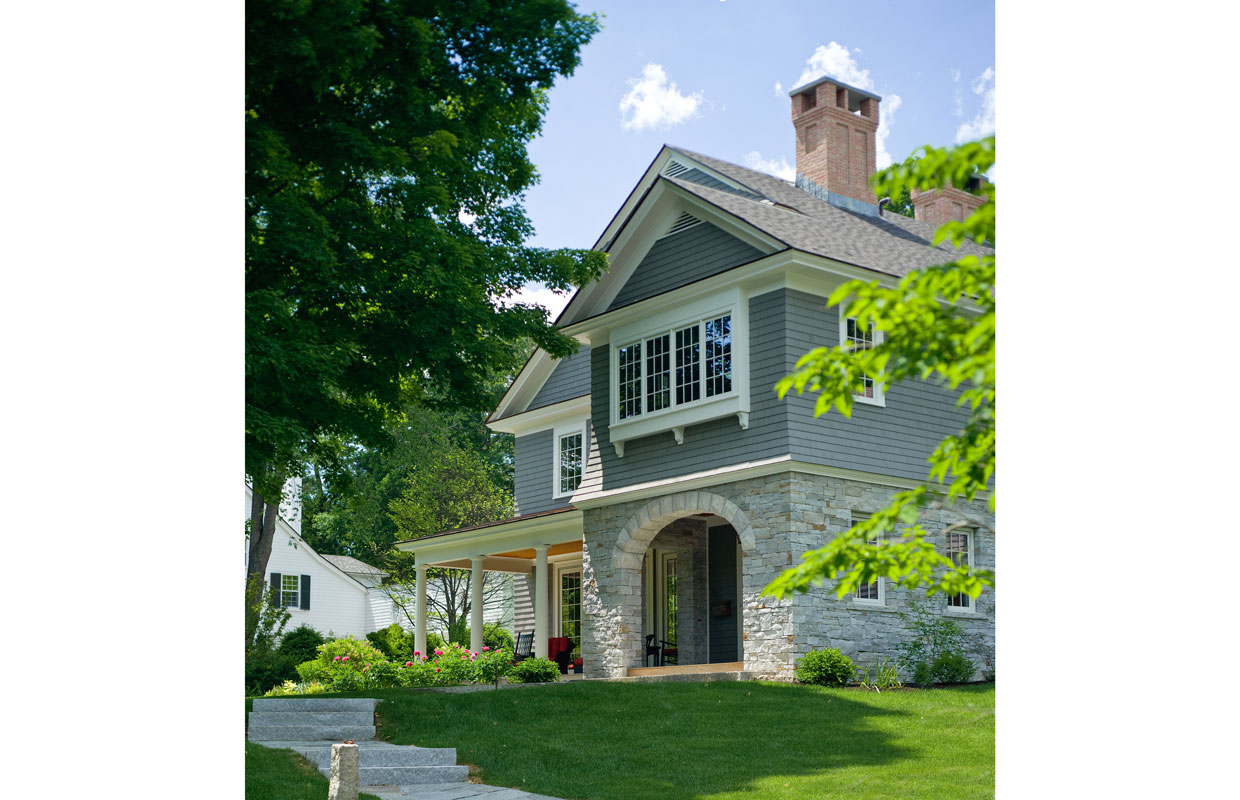 front view of a shingle style home with stone accents and a green grass lawn