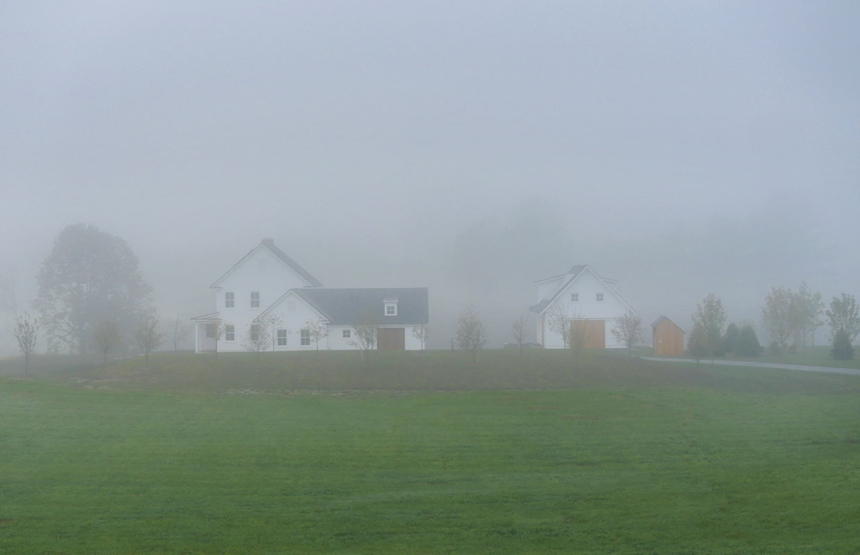 white farmhouse in a foggy field