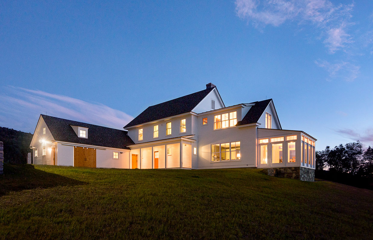 large white farmhouse on a hillside at dusk