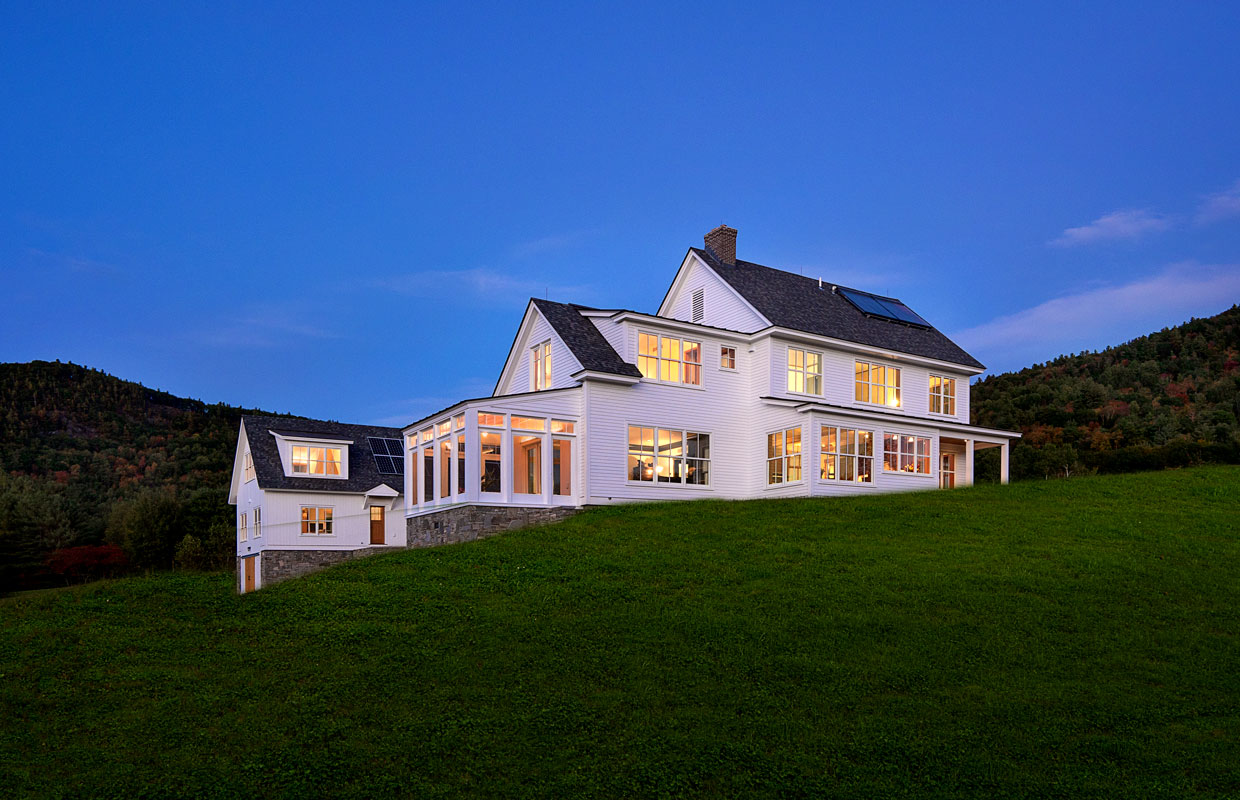 large white farmhouse on a hillside at dusk
