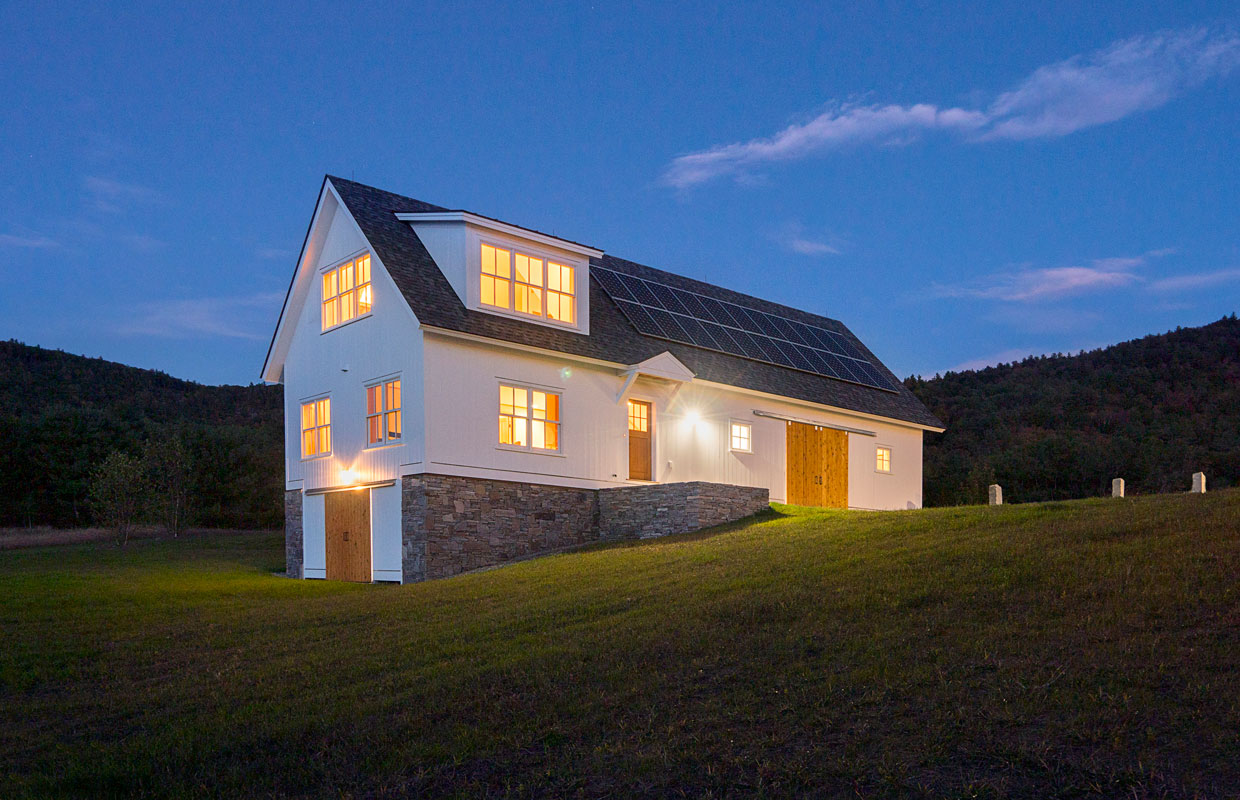 large white barn on a hillside at dusk