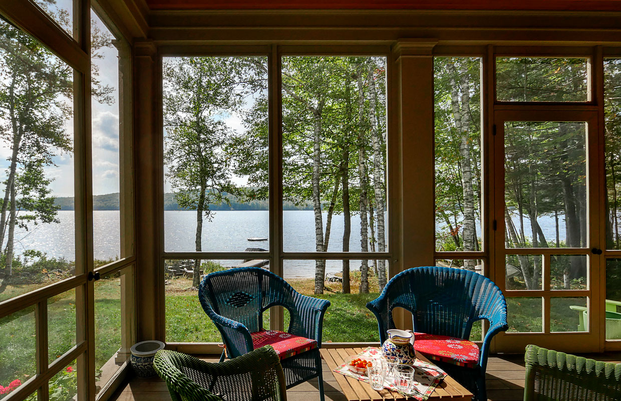 view of a lake from inside a 3 season porch