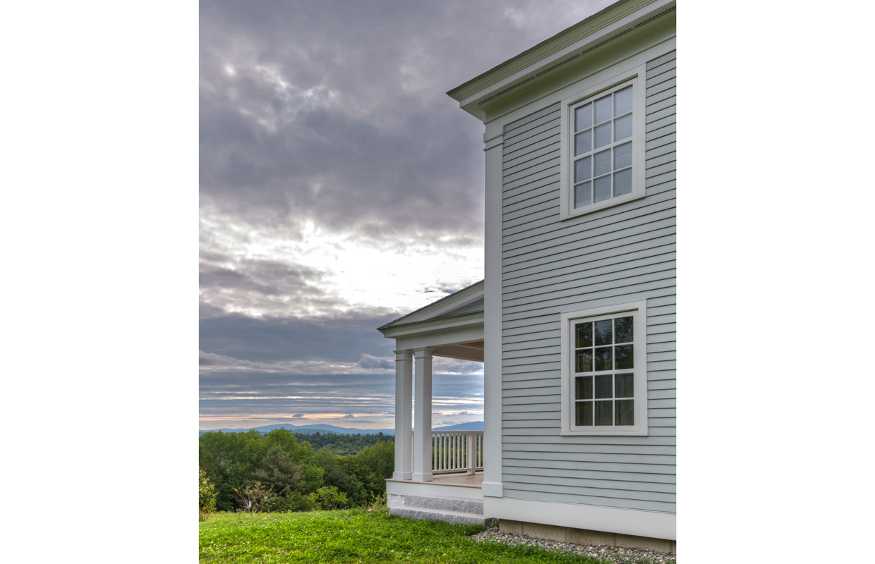 mountain view from the yard of a large gray colonial home