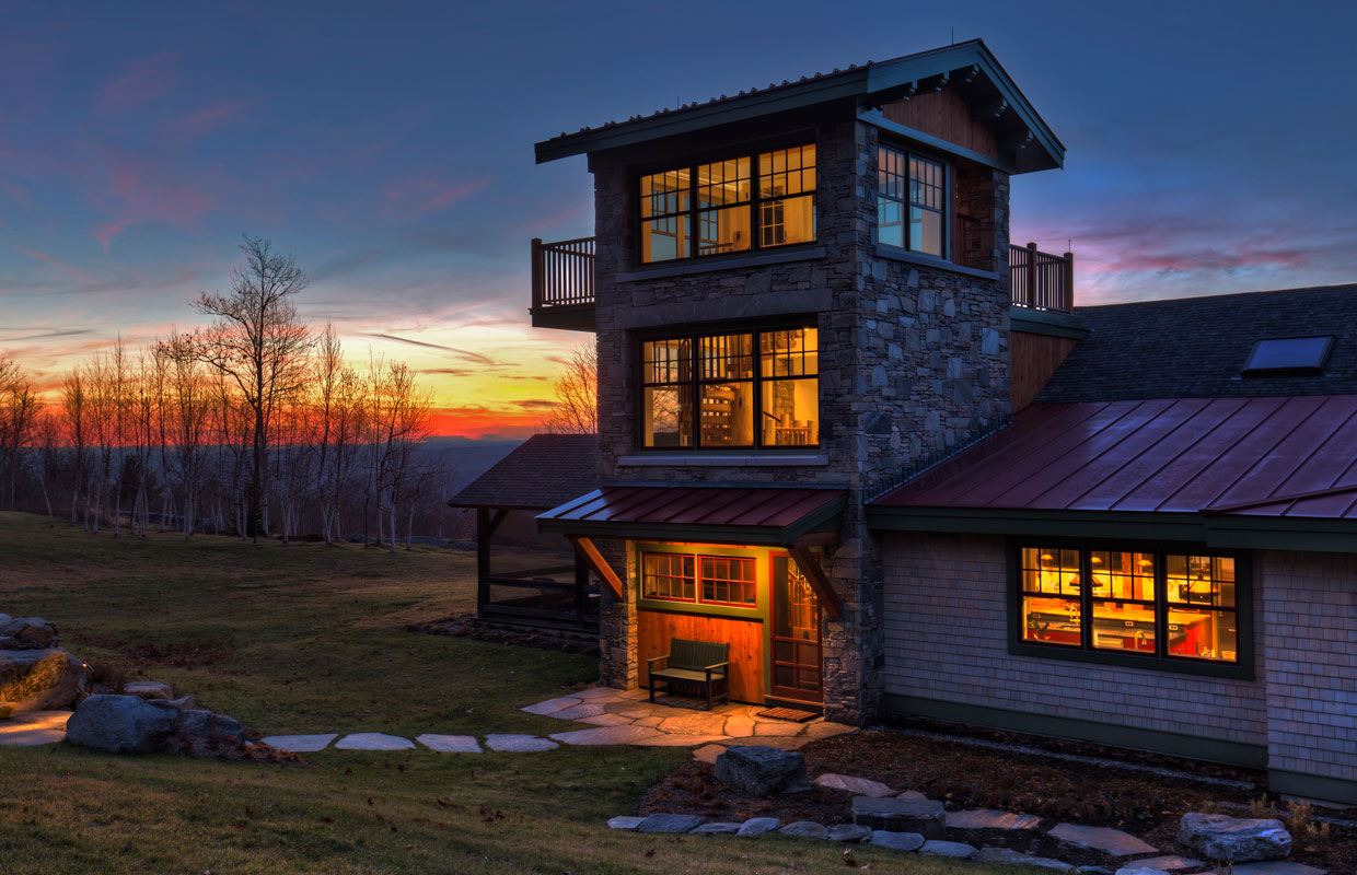 stone tower with a suspended deck on a home with a mountain view in the background at sunset