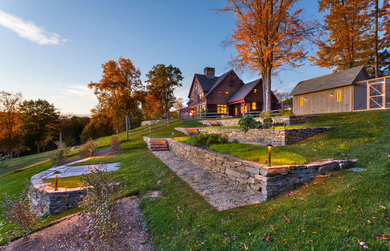 house on a hill with a barn and lots of stone work built into the hillside