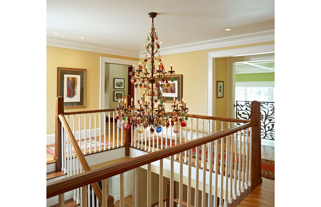 top of a staircase with a wrap around rail and hanging light fixture