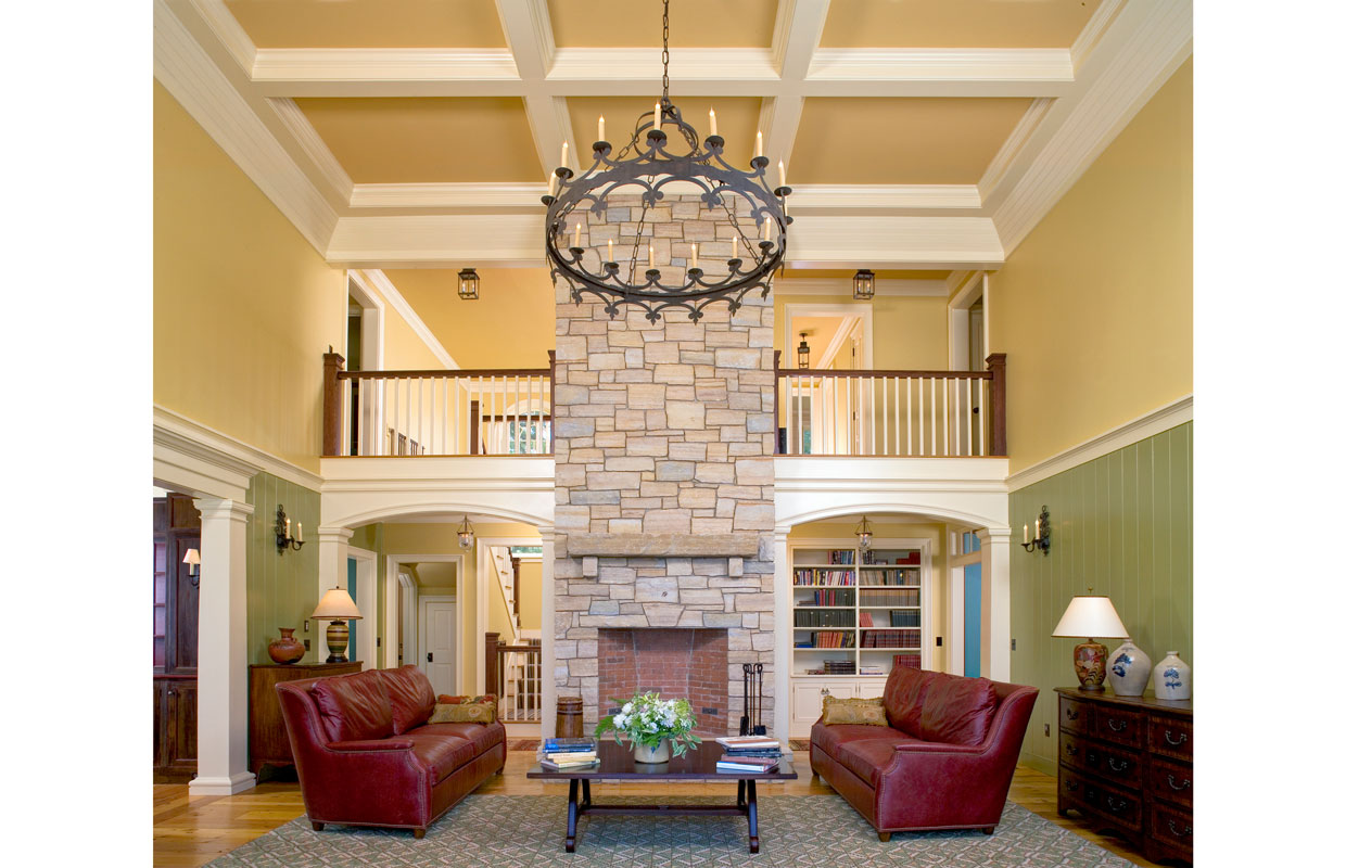 great room with view of a balcony and a large stone fireplace and chimney in the center of the room