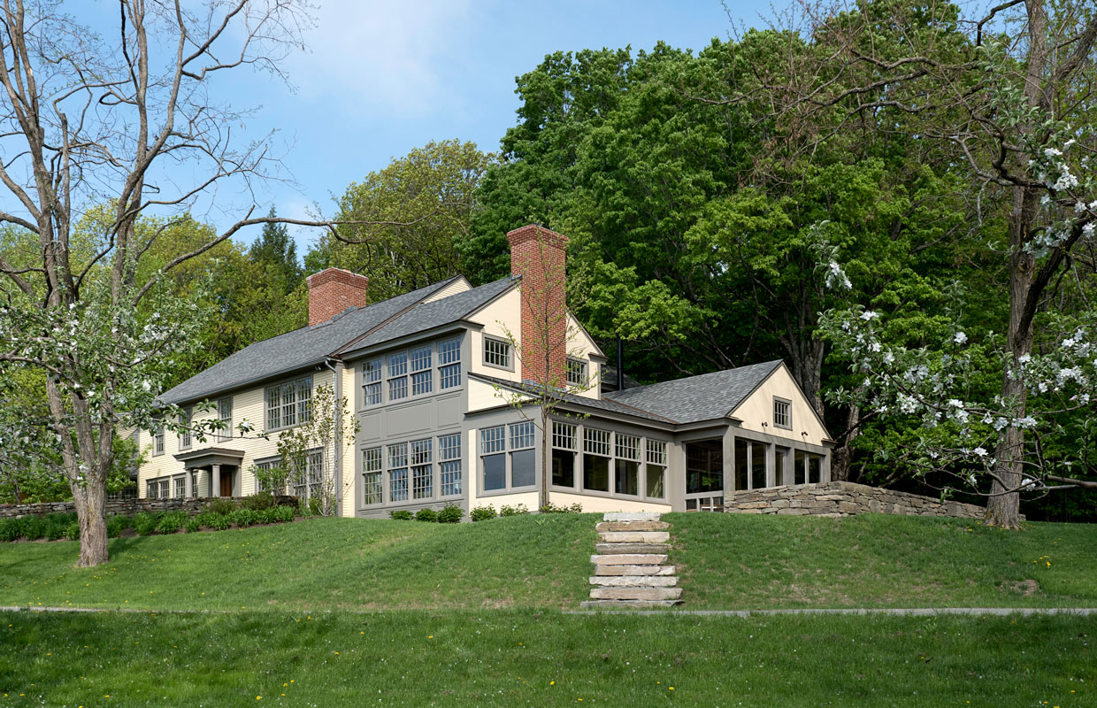 big cream house with a large lawn and stone steps