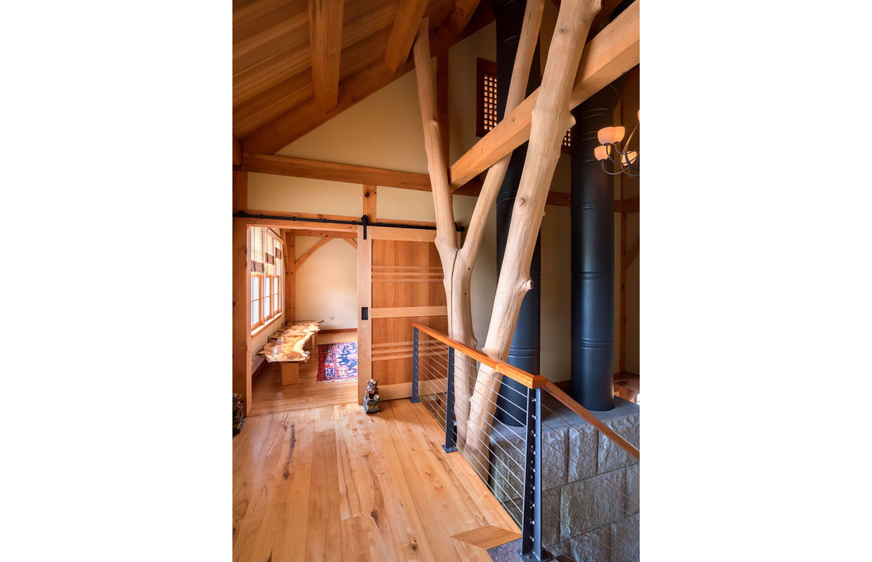 top of a staircase showing a natural tree trunk post and hardwood floors