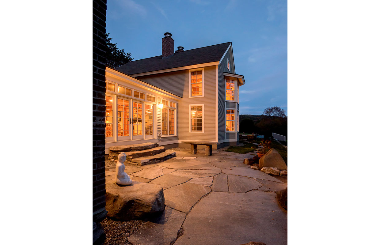 gray house at dusk with a patio and buddha statue